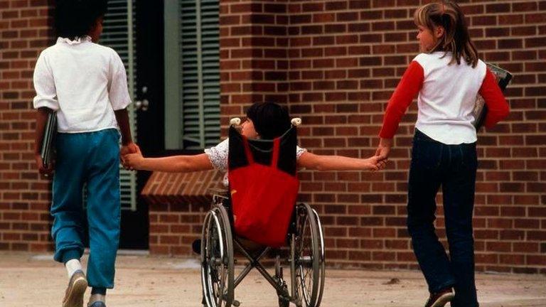 Physically handicapped child holds hands with friends