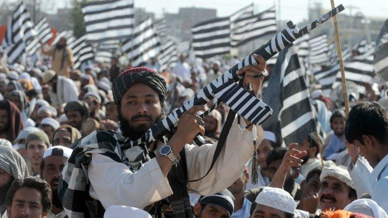 A supporter of the Islamist party Jamiat Ulema-e-Islam Fazl (JUI-F) poses with a false gun at an election rally in Lahore on March 31, 2013.