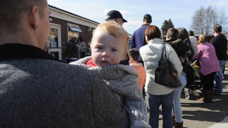 11 month old baby boy held in his father's arms as they queue outside Morriston Hospital in Swansea