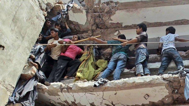 Bangladeshi rescuers squeeze through a gap to help pull out survivors spotted in the debris of a building that collapsed in Savar, near Dhaka, Bangladesh, on Wednesday