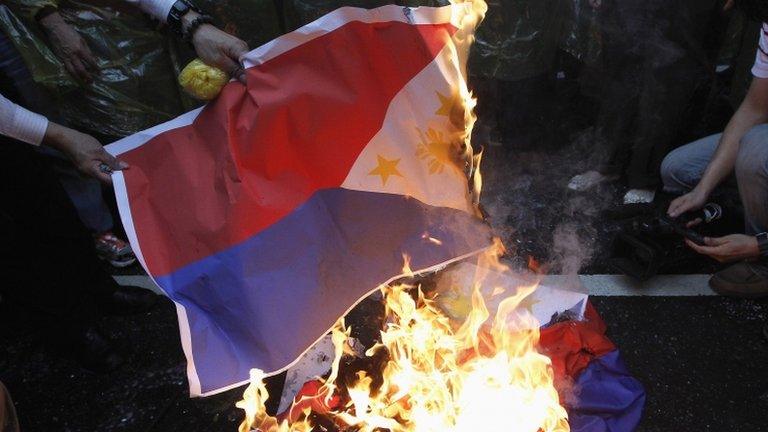 Activists burn Philippine national flags in front of the Manila Economic and Cultural Office, the de facto Philippine embassy in Taiwan, during a protest against the Philippine government in Taipei on 13 May 2013