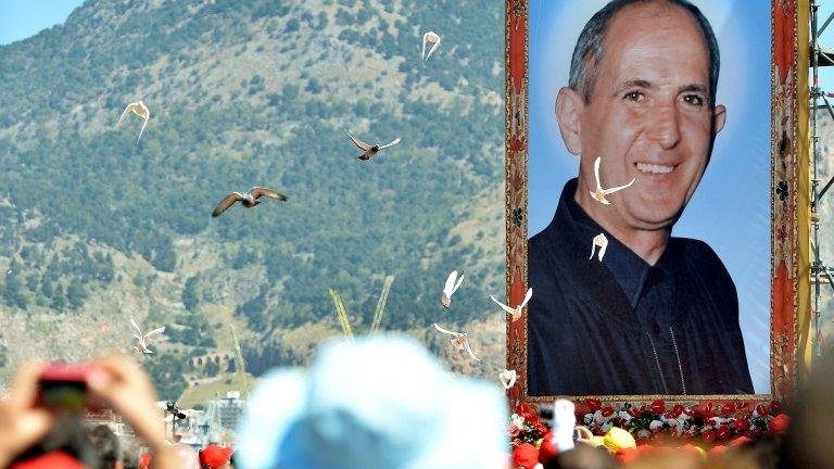 A portrait of Father Giuseppe "Pino" Puglisi, an outspoken anti-Mafia advocate, hangs over about crowd during his beatification ceremony in Palermo on May 25, 2013.