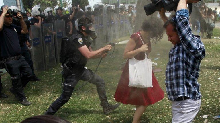 A Turkish riot policeman uses tear gas against Ceyda Sungur in Taksim Square