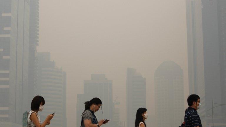 Office workers wearing masks make their way to work in Singapore's central business district on 21 June 2013