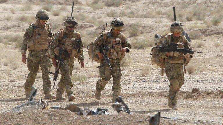 Four British soldiers in desert terrain