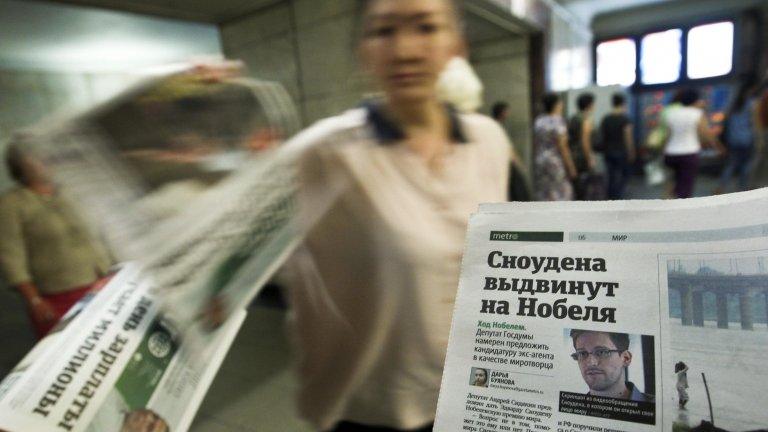 An employee distributes newspapers with a photograph of Edward Snowden seen on a page, at an underground walkway in central Moscow on 2 July 2013