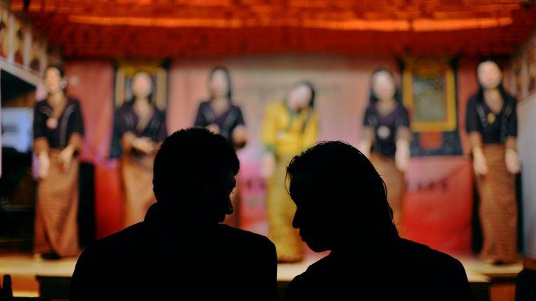 Two Bhutanese men sit in a Karaoke bar as they watch a group of girls dance in Thimphu on June 2, 2013.