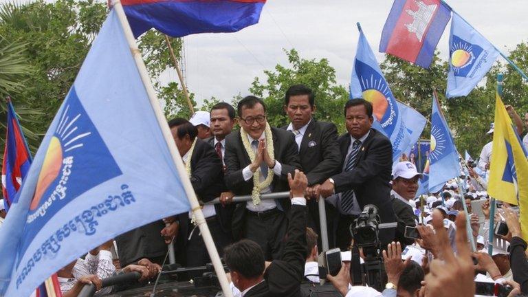 Sam Rainsy, centre, greets his supporters on arrival in Phnom Penh, Cambodia, on 19 July 2013