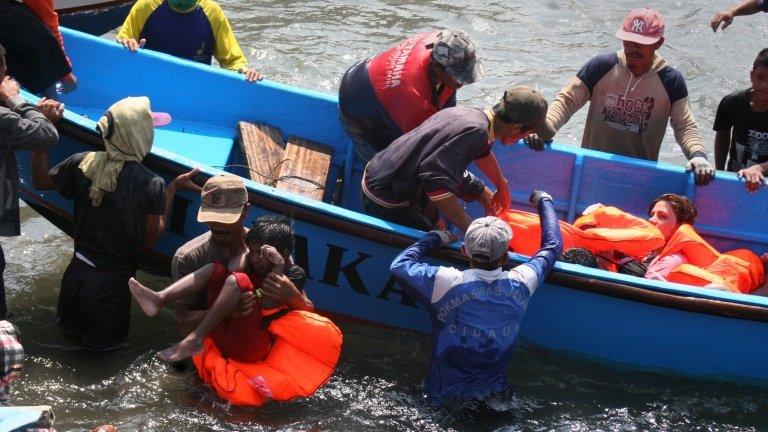 Rescuers assist survivors arriving on fishing boat at the wharf of Cidaun, West Java on July 24, 2013 after an Australia-bound boat carrying asylum-seekers sank off the Indonesian coast