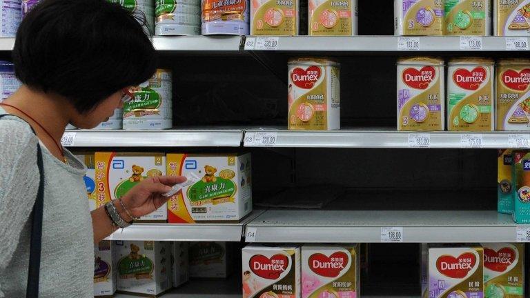 A woman checks the price beside a shelf of Dumex baby formula which uses the New Zealand dairy Fonterra as its raw material supplier