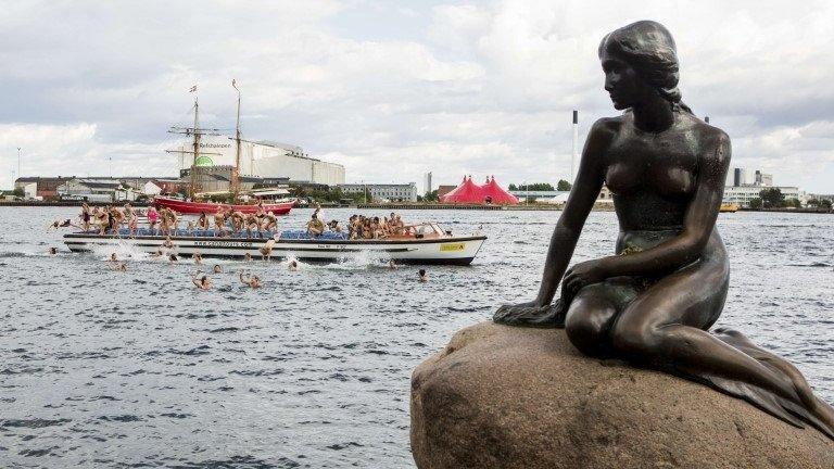 Women swim around the Little Mermaid. Photo: 23 August 2013