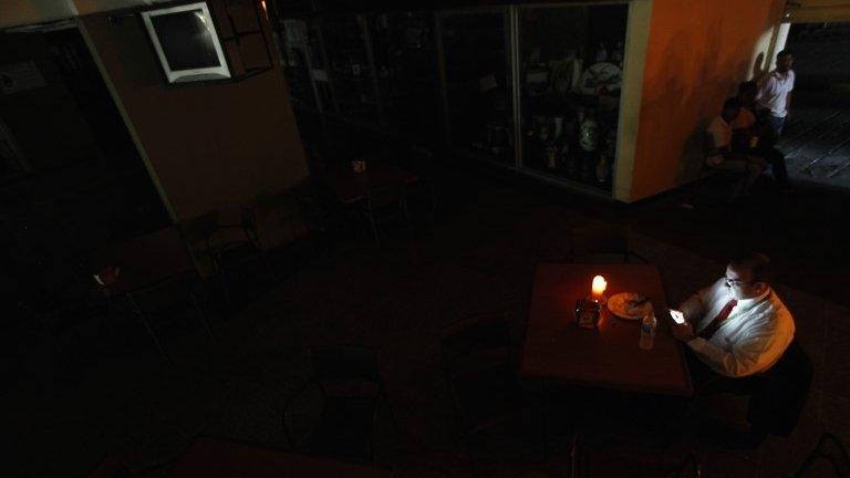 A man sits down to have lunch by candlelight, during a massive blackout in Caracas September 3,2013