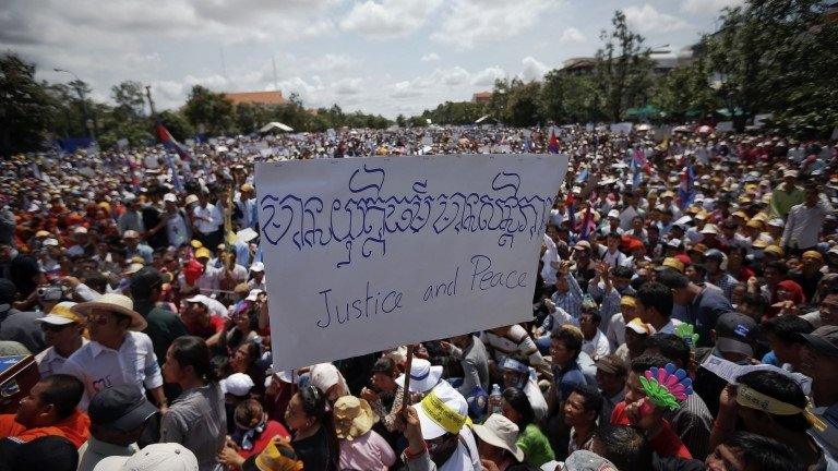 A supporter of Cambodia National Rescue Party (CNRP) holds a banner among others attending a rally in Phnom Penh