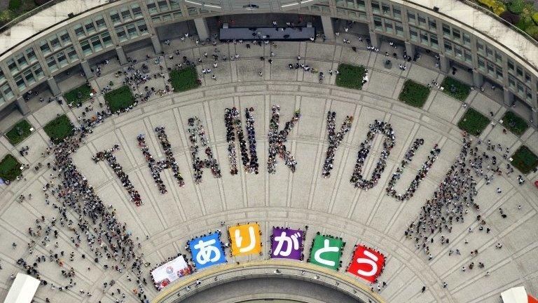 Citizens form "Thank you" to celebrate at the Tokyo Municipal Government office square in Tokyo Sunday, 8 Sept. 2013 after the International Olympic Committee chose the city to host the 2020 Olympics