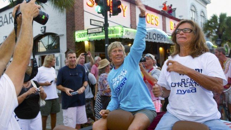 Endurance swimmer Diana Nyad (L) and her chief handler Bonnie Stoll (R) ride in vehicle during a parade past Sloppy Joe"s Bar in Key West, Florida 3 September 2013