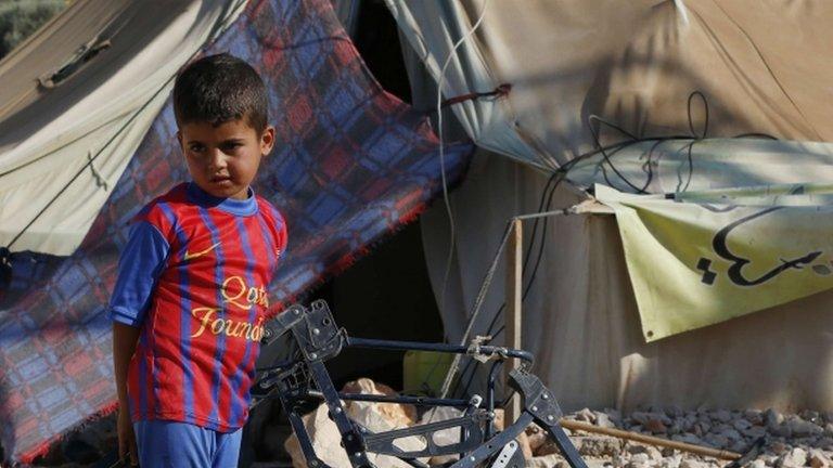 Child stands outside a tent in a refugee camp in Lebanon