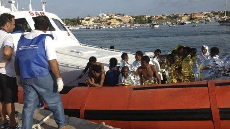 Rescued migrants arrive onboard a coastguard vessel at the harbour of Lampedusa