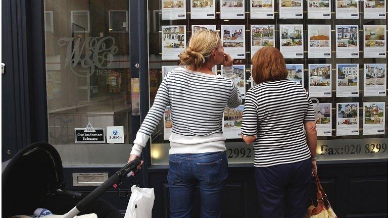 People browsing an estate agent's window