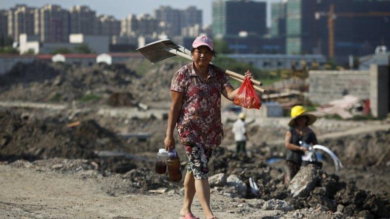 A female migrant construction worker walks towards her dormitory after a shift at a residential construction site in Shanghai on 6 August 2013