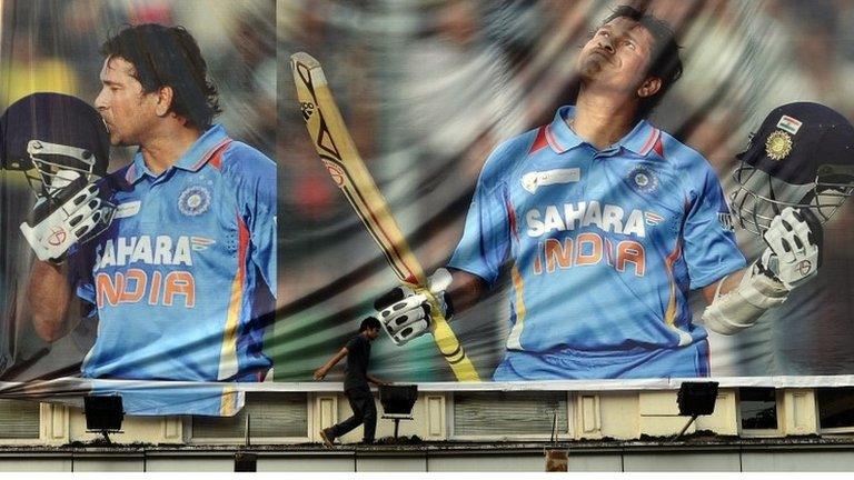 An Indian youth walks past a huge poster saluting cricketer Sachin Tendulkar on the facade of a shop in Mumbai on 13 November 2013