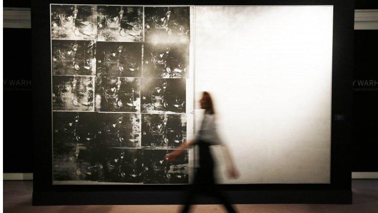 A Sotheby's employee poses with Andy Warhol's artwork Silver Car Crash