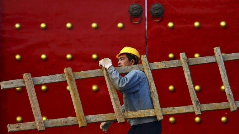 A worker carrying a ladder walks past a palace used by ancient emperors in Shenyang, Liaoning province