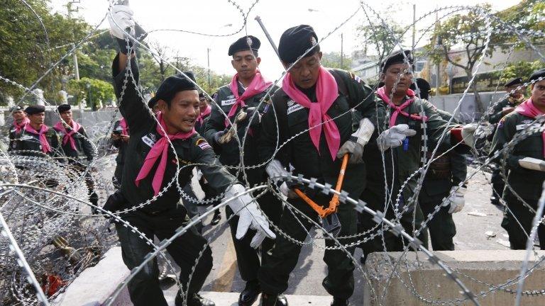 Thai police remove barbed wire outside the city police headquarters in Bangkok on 3 December 2013