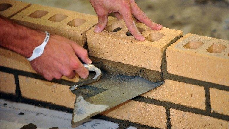 A close-up of a brick-layer's hands