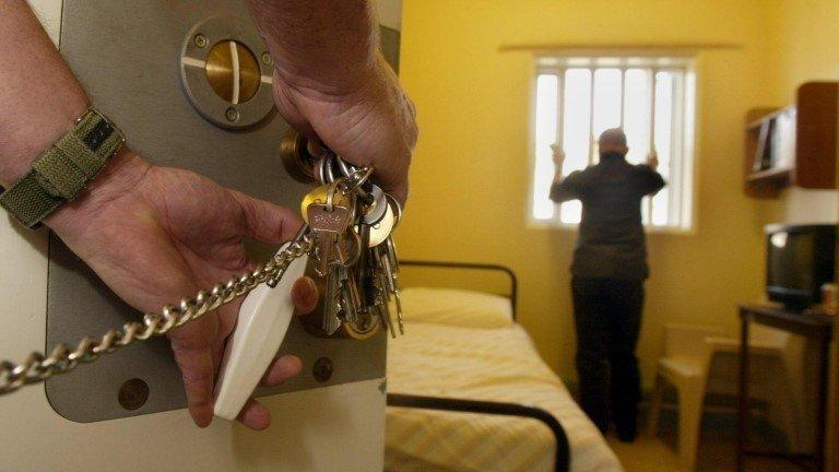 A prisoner standing in his cell as a guard puts his keys in the lock