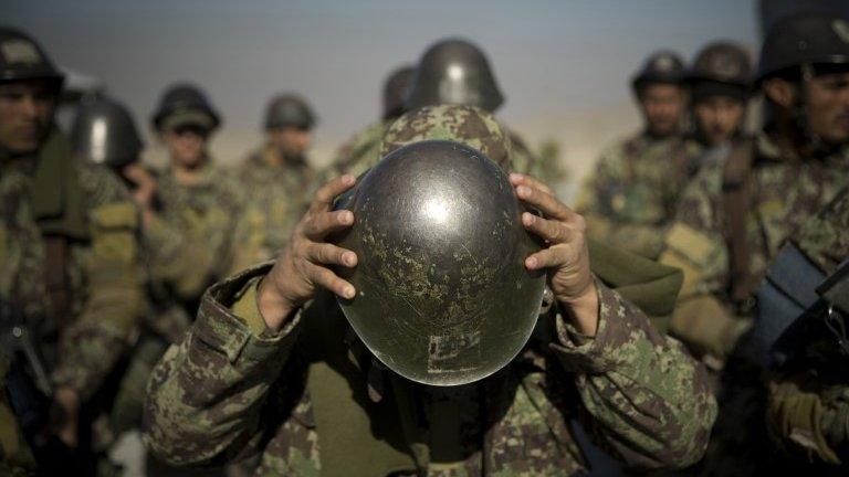 An Afghan army soldier adjusts his helmet as he lines up with others at a training facility in the outskirts of Kabul, Afghanistan