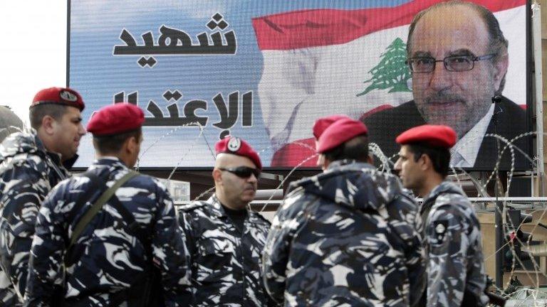 Members Lebanese army stand guard by a poster of Mohammed Chatah, who was assassinated on Friday by a car bomb, during his funeral procession at Mohammed at Martyrs" Square in Beirut, Lebanon, Sunday, Dec. 29, 2013