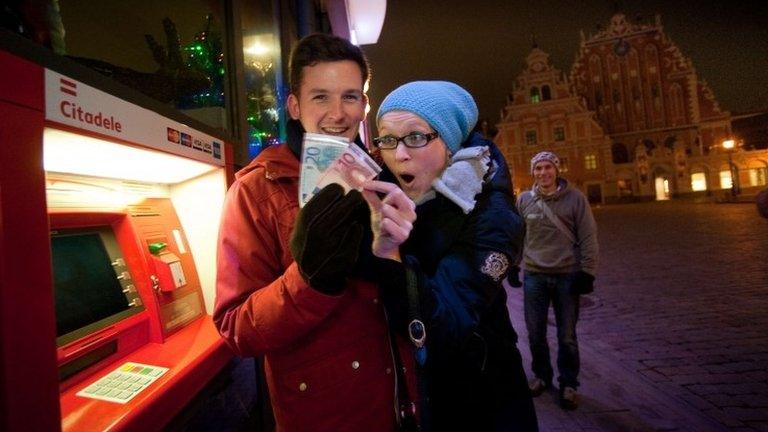 A man and woman withdraw euros from a cash machine in Riga, 1 January