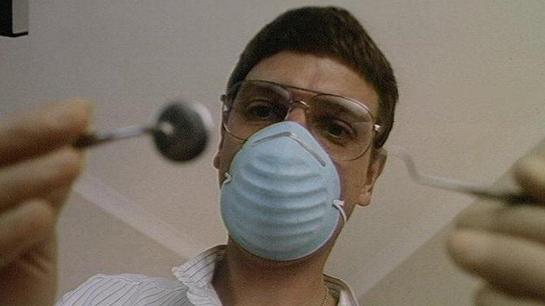 Dentist with mask, holding tools