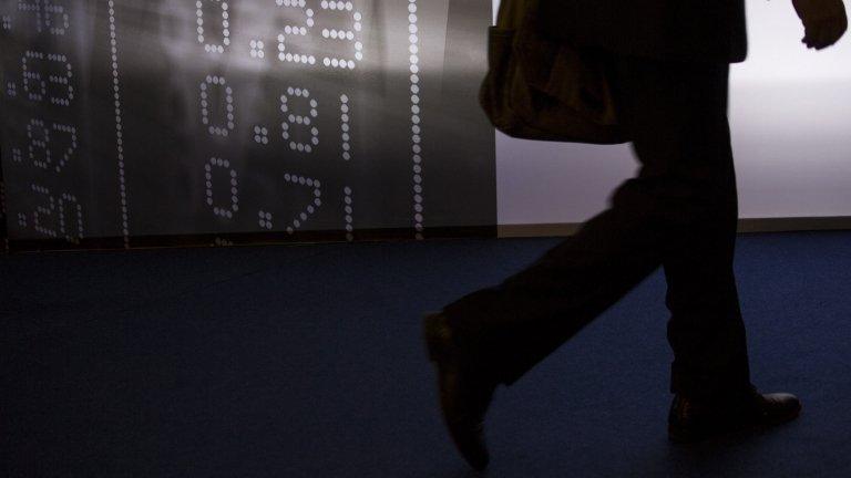 Man walks past board showing market data