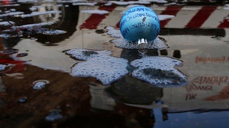 Reflection of van driving past Christmas bauble floating in water