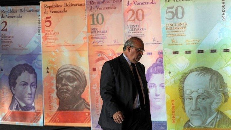 A man walk in front of posters of Venezuelan bills in Caracas