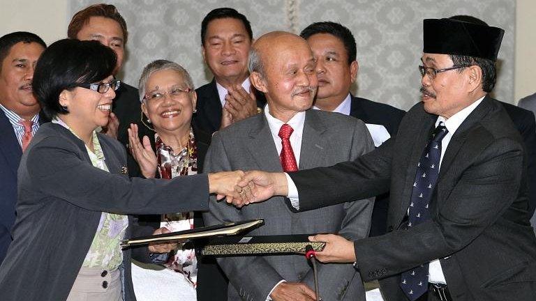 Miriam Coronel Ferrer (L), chairperson of the government negotiating panel, exchanges documents with MILF Chief Negotiator Monagher Iqbal (R) during a press conference at a hotel in Kuala Lumpur on January 25, 2014.