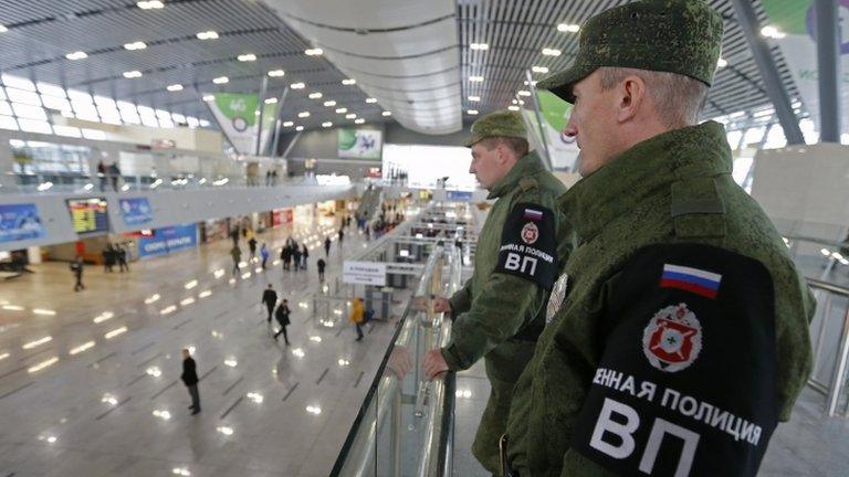 Military police officers stand guard at a train station in the Adler district of Sochi