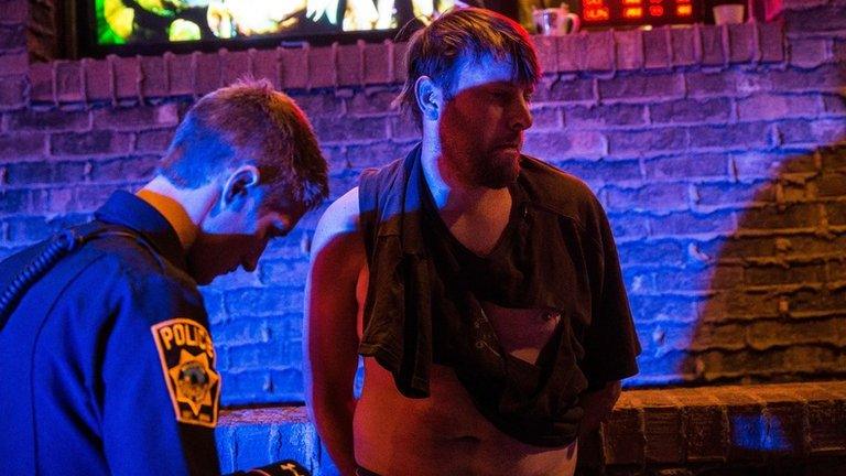 An intoxicated man sits inside an ambulance outside a bar on in Williston, North Dakota, on 26 July 2013