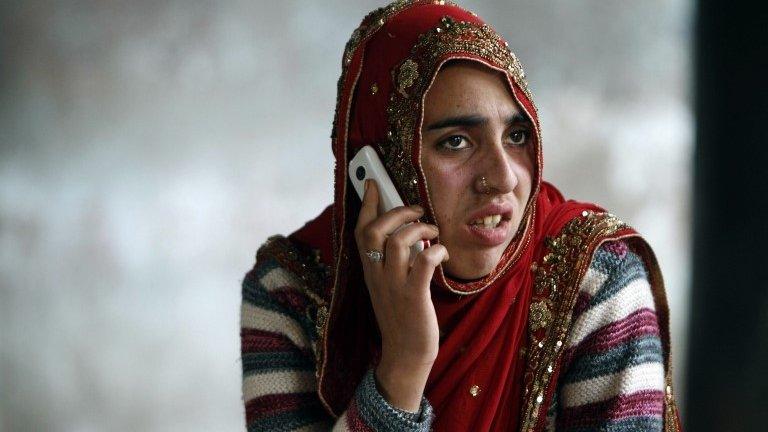 A stranded Indian passenger speaks on her mobile phone as she waits for the Jammu-Srinagar highway to reopen at a bus station in Jammu, India, Wednesday, Jan. 1, 2014.