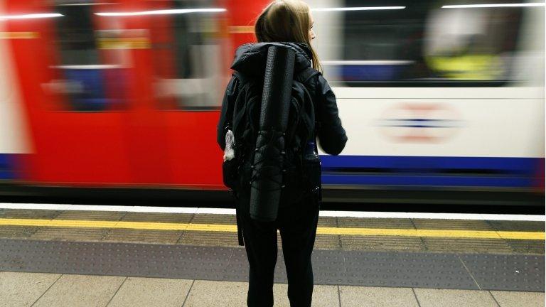 A woman waits for a London Underground train to stop at Oxford Circus station in central London