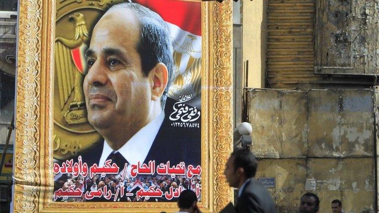 People walk past a large poster of Abdul Fattah al-Sisi in Cairo (26 March 2014)