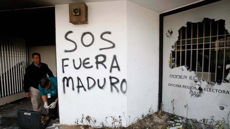 Police officers inspect the national electoral headquarters after a fire, which was set by anti-government protesters according to government officials, in Maracaibo on 25 March, 2014