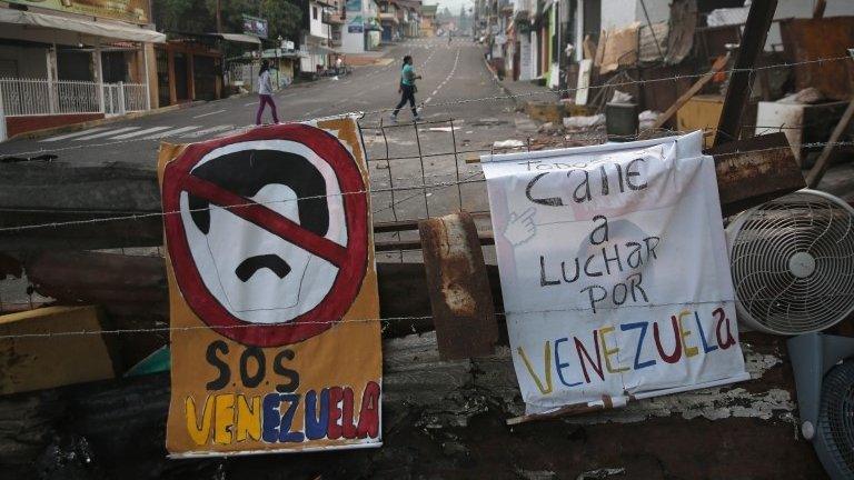 Women walk past protesters' barricades on 8 March, 2014, in San Cristobal