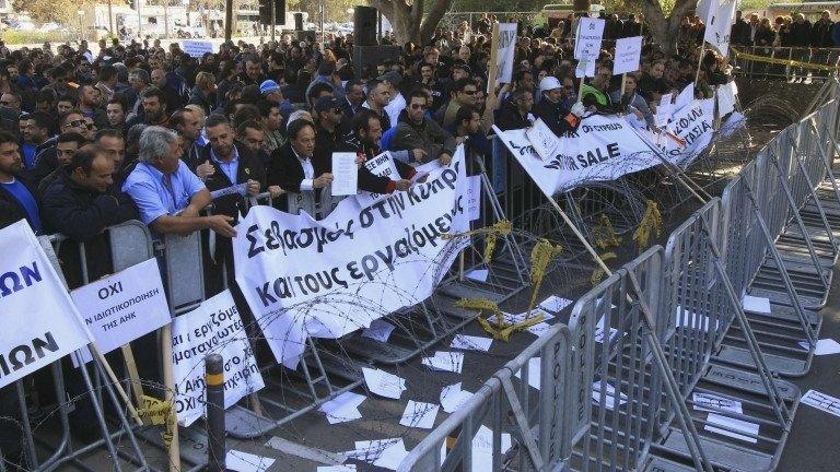 Demonstrators hold signs and banners outside Cyprus’s parliament as they protest plans by the government in Nicosia 27/02/14.