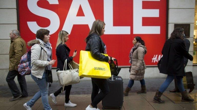 Shoppers on Oxford Street in front of a sale sign