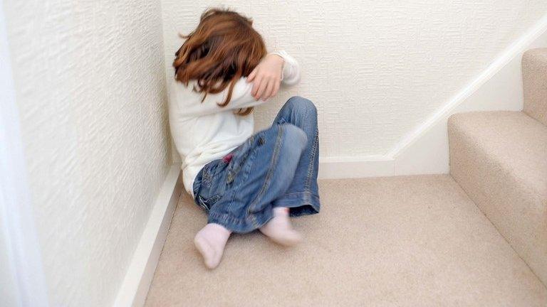 Young girl on stairs hiding her face