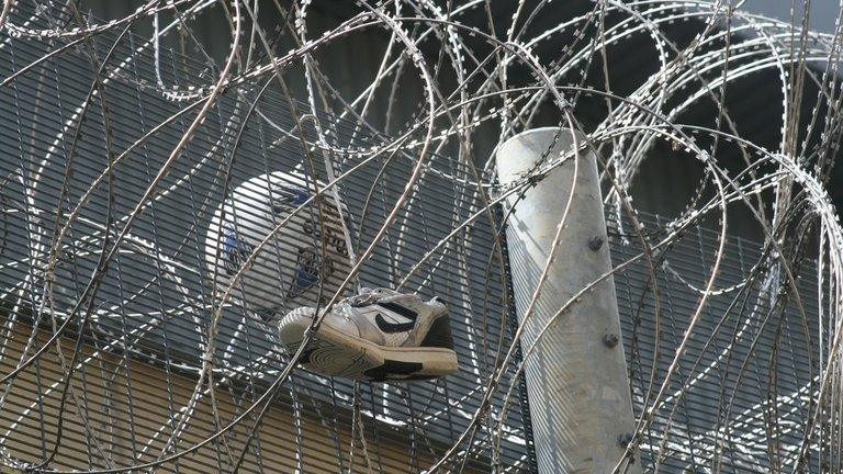 Football and running shoe on top of barbed wire