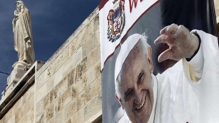 A banner showing a picture of Pope Francis is displayed from the wall of the Church of St Catherine, which adjoins the Church of the Nativity (18 May 2014)