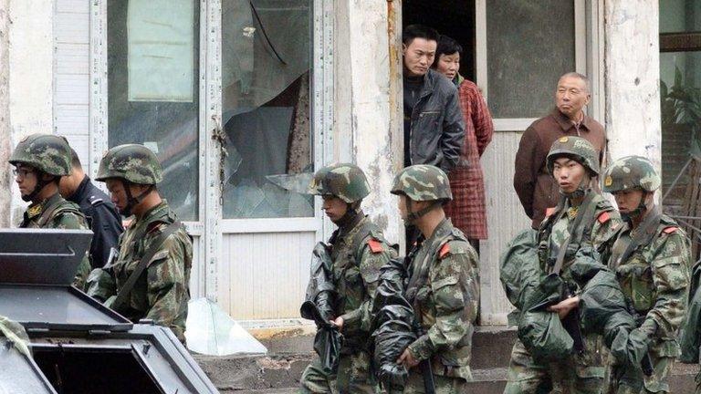 Paramilitary policemen patrol past a building, where a window was damaged by an explosion in Urumqi on Thursday, in the Xinjiang Uighur Autonomous Region, in this photo taken by Kyodo on 22 May 2014